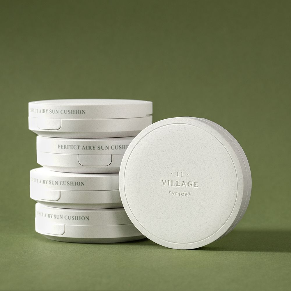 Gestapelde cushion crème verpakkingen. Opschrift: PERFECT AIRY SUN CUSHION en VILLAGE FACTORY. Witte, ronde verpakkingen.