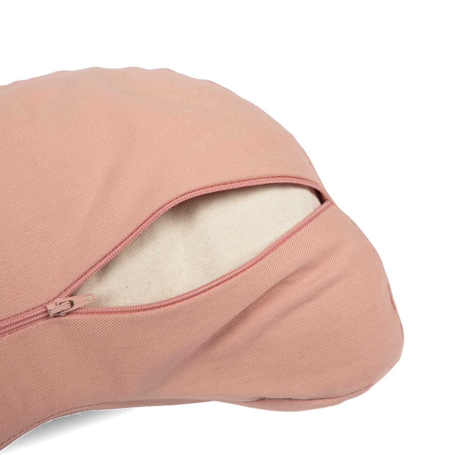 Gros plan de la fermeture éclair ouverte d'un coussin de méditation rose, révélant l'intérieur.