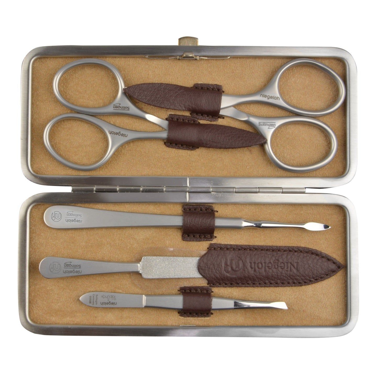 Open manicure etui. Schaar, pincet, nagelvijl en andere zilverkleurige metalen tools. Bruin lederen details. Niegeloh Solingen.