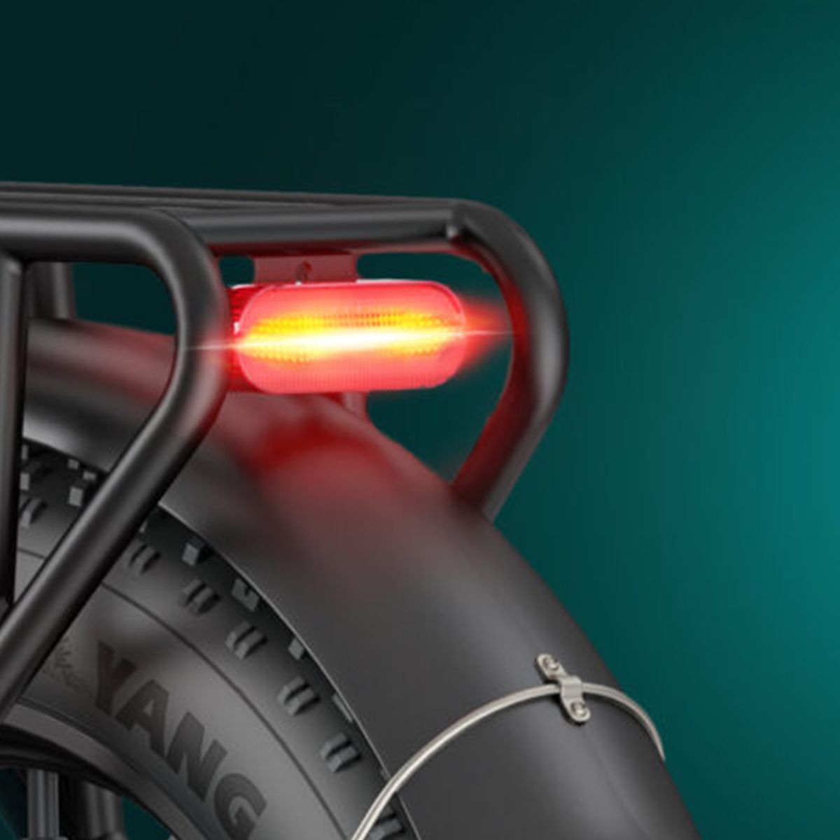 Feu arrière d'un vélo noir. Lumière rouge, monté sur un porte-bagages. Pneu noir avec inscription.