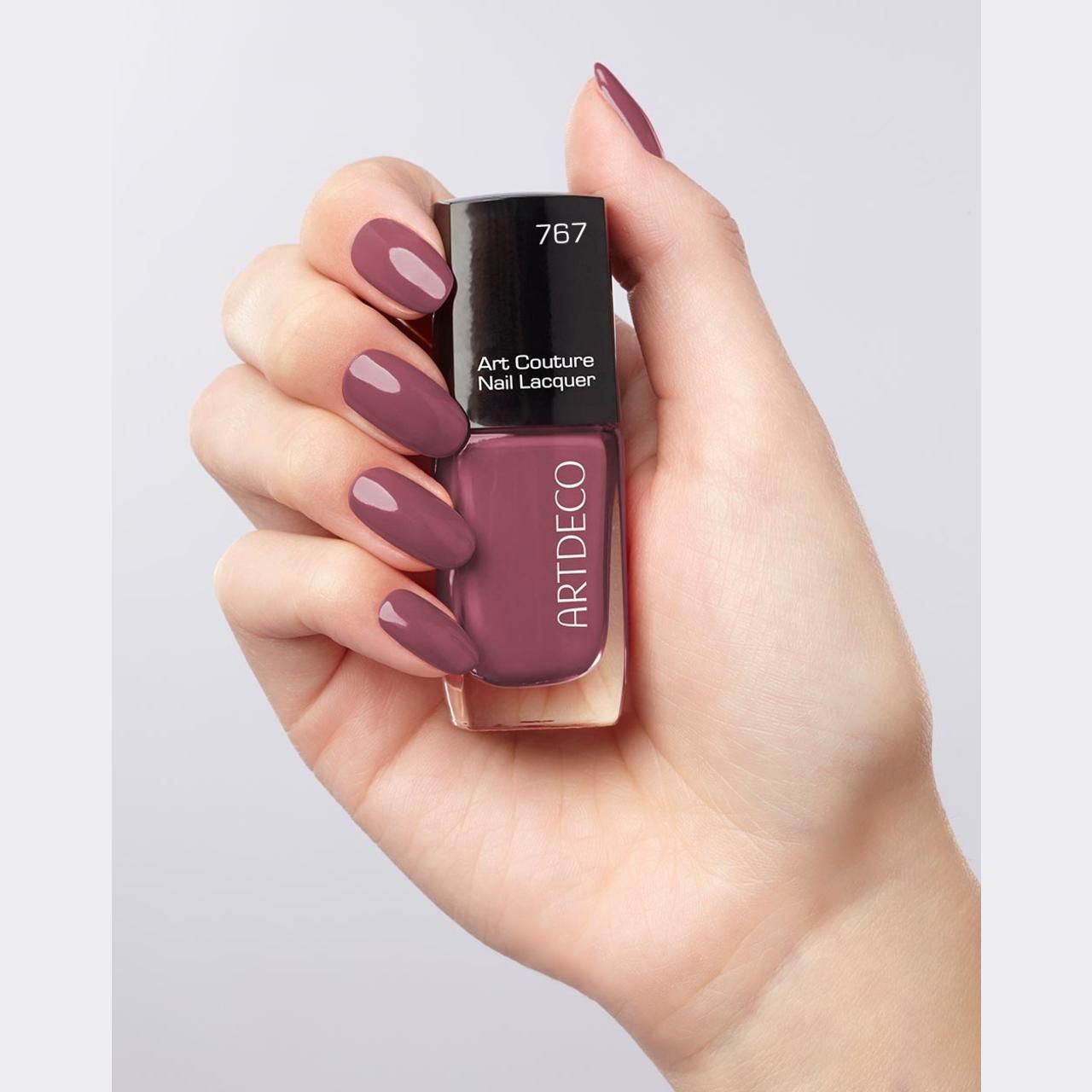 Hand houdt nagellakfles en gelakte nagels vast. Nagellak: roze tint. Opschrift "767" en "Art Couture Nail Lacquer". Merk: ARTDECO.