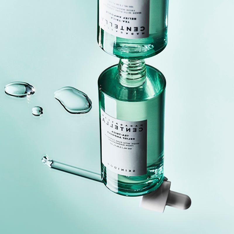 Deux flacons en verre vert avec bouchons et pipettes blancs. Étiquettes et gouttes de liquide. SKIN1004.