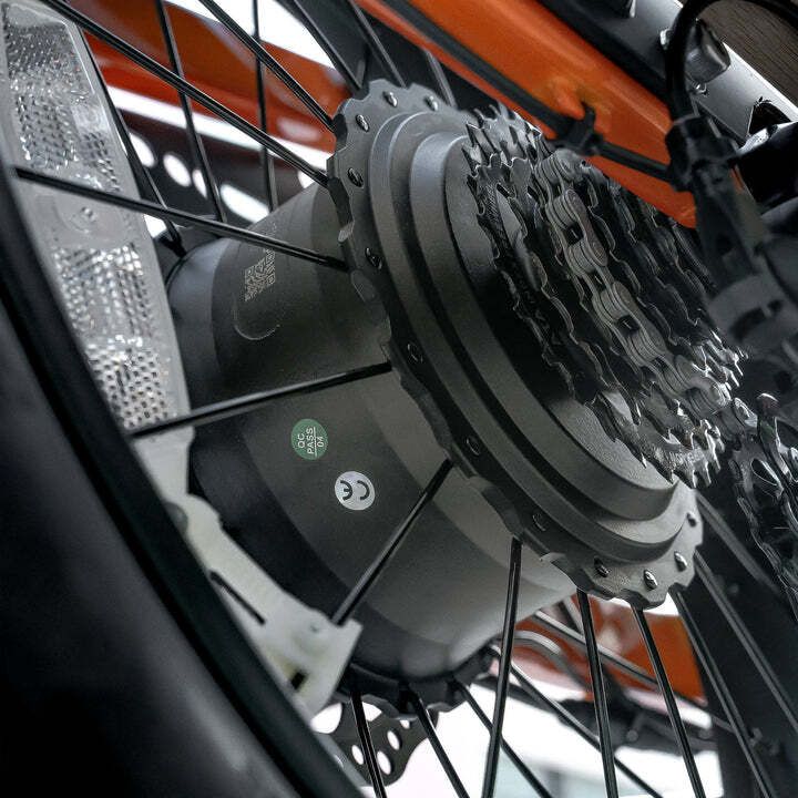 Close-up van het achterwiel van een e-bike. Tandwielen, ketting en motor zichtbaar. CE-markering.