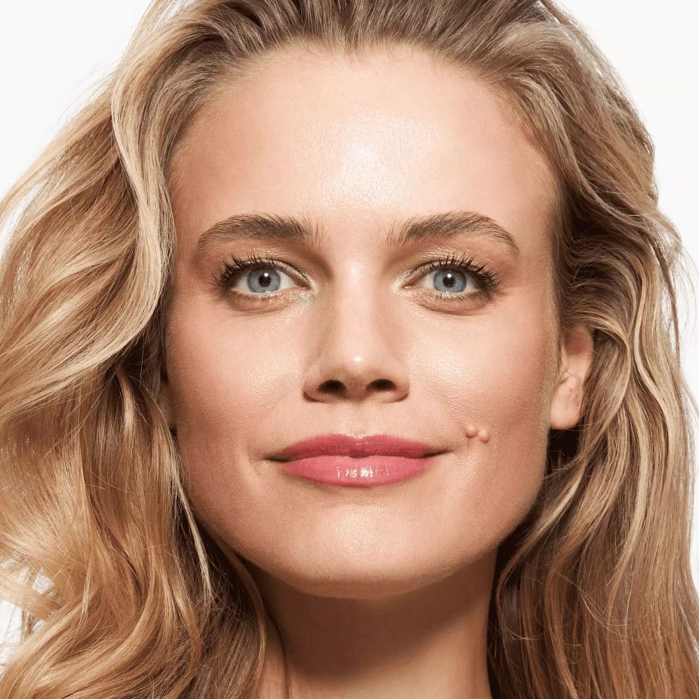 Portrait d'une femme aux cheveux blonds. Elle porte du rouge à lèvres. Arrière-plan : blanc.