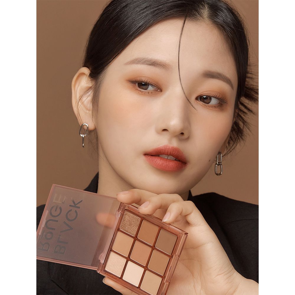 Femme tenant une palette de fards à paupières. Le produit présente neuf teintes. Le nom de la marque BLACK ROUGE est visible.