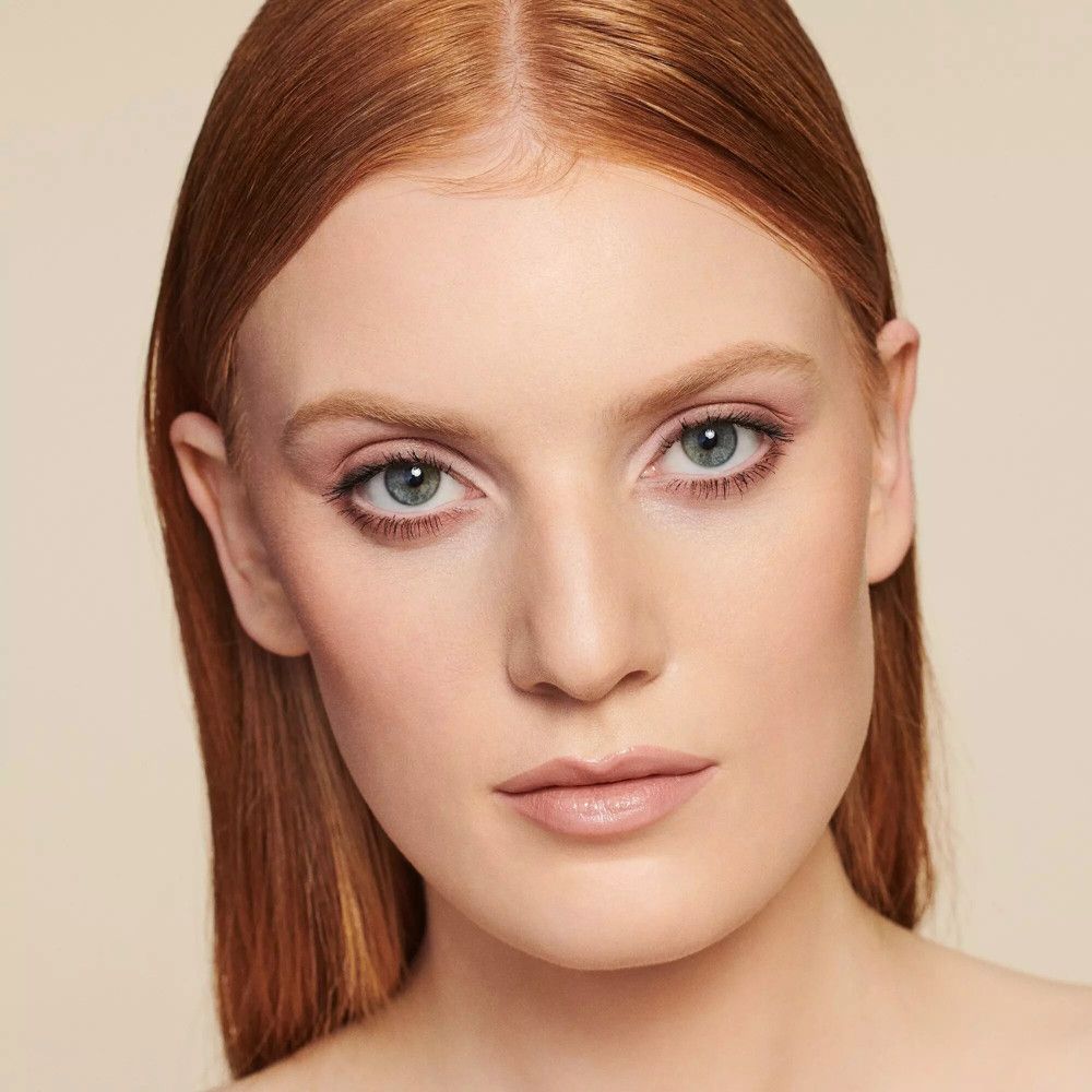 Portrait d'une femme aux cheveux roux et maquillage discret. Accent sur les yeux et les lèvres.