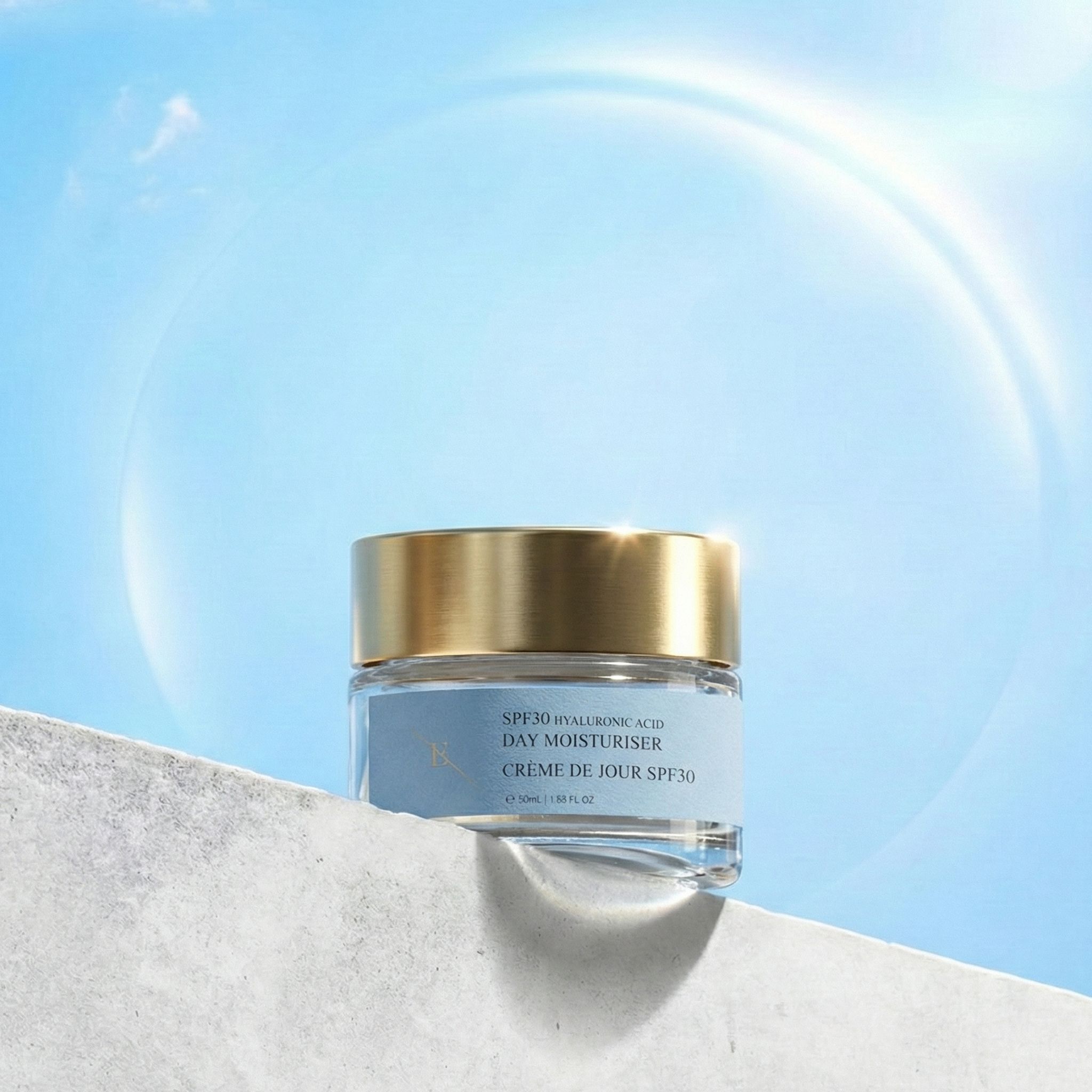 Dagcrème potje met gouden deksel voor blauwe hemel. Opschrift: SPF30 Hyaluronic Acid Day Moisturiser, Crème de Jour SPF30.