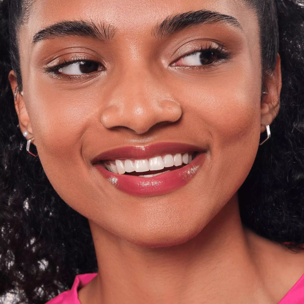 Femme avec teinte à lèvres. Lèvres brillantes, brunes. Haut rose. Gros plan.