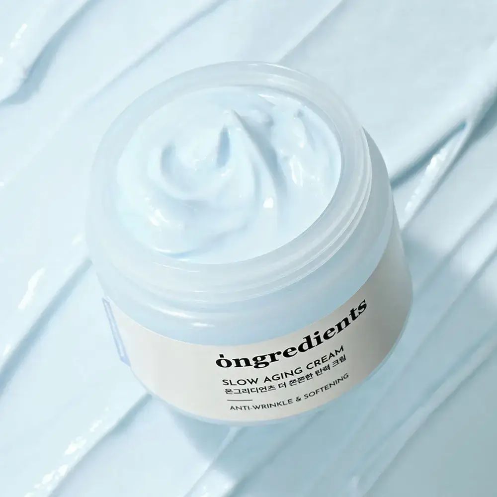 Pot de crème ouvert avec de la crème. Inscription : Ongredients, Slow Aging Cream, Anti-Wrinkle & Softening.