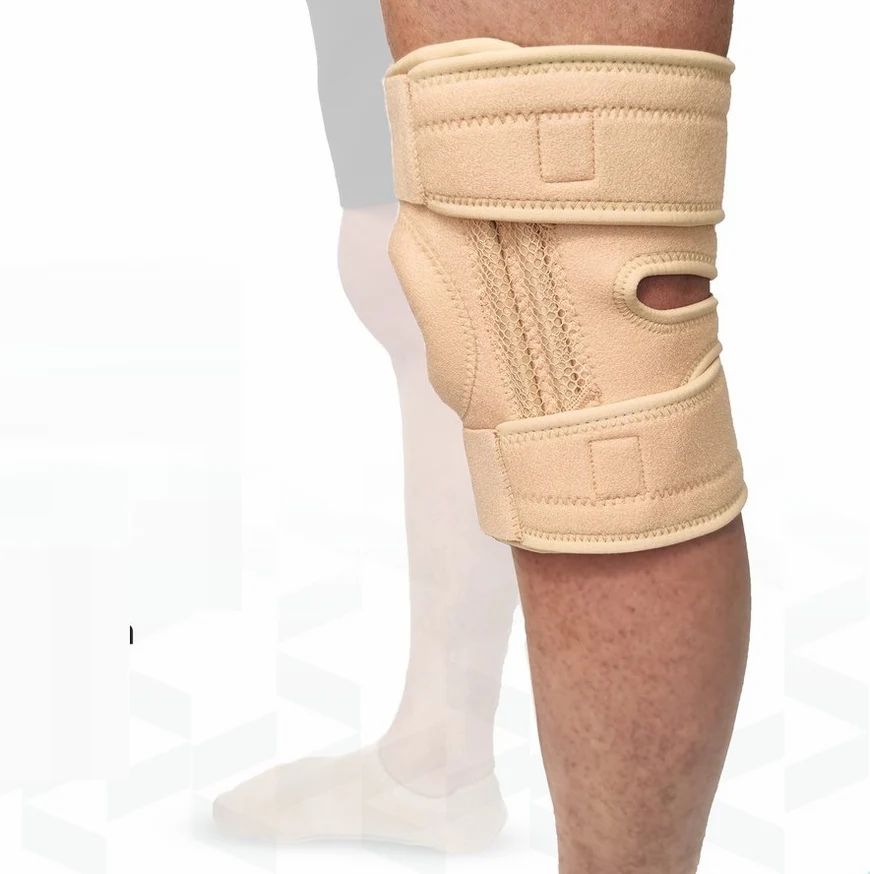 Genouillère beige sur une jambe. Fermetures velcro et ouverture rotulienne visibles.