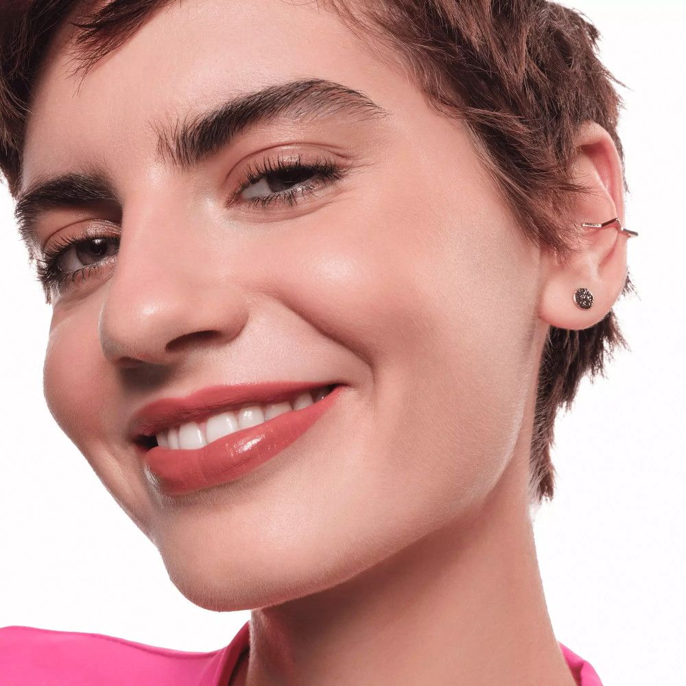 Portrait d'une femme avec du rouge à lèvres rose. Elle sourit.