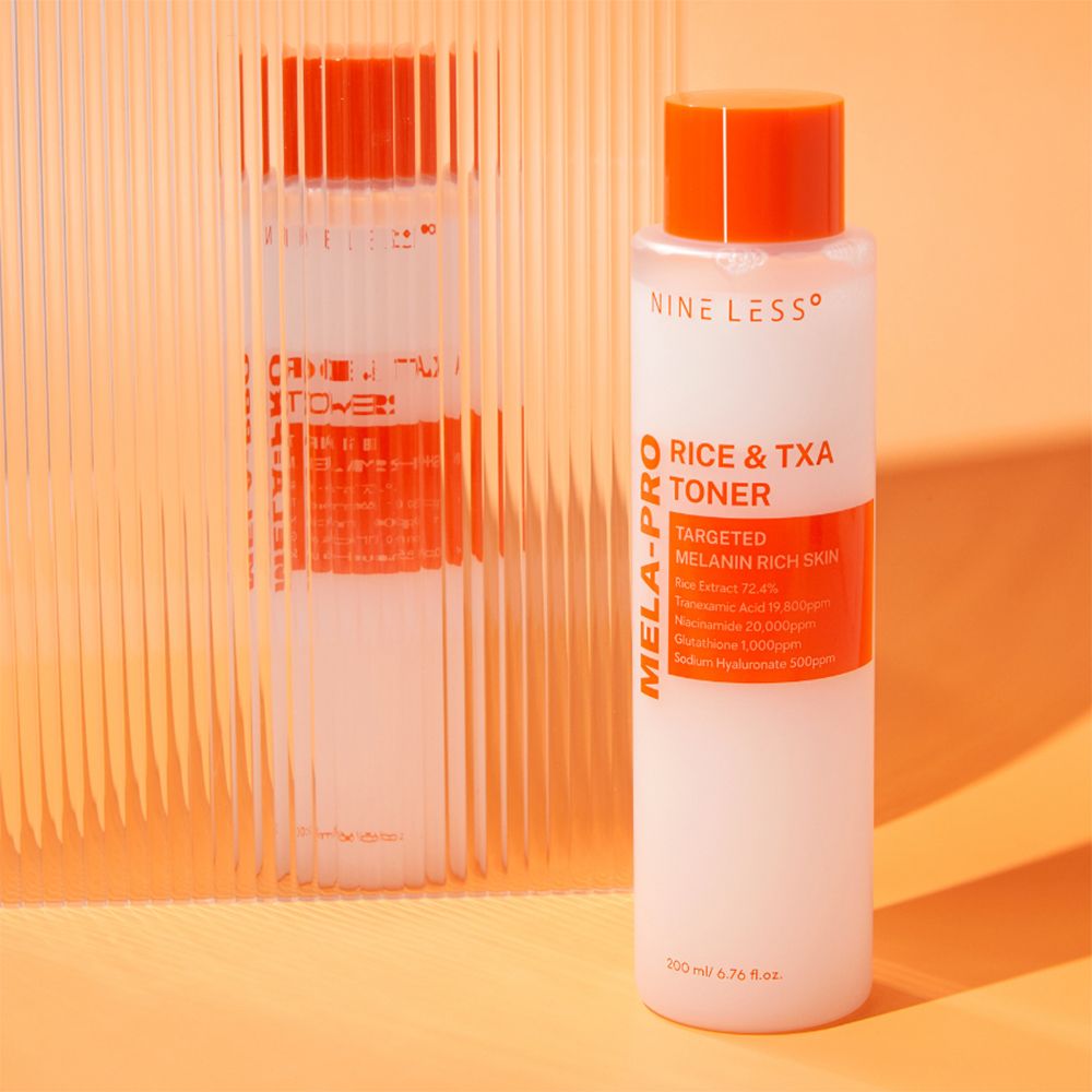 NINE LESS Mela-Pro Rice & TXA Toner fles, wit met oranje accenten, voor een gestructureerde achtergrond. Productnaam en details zichtbaar.