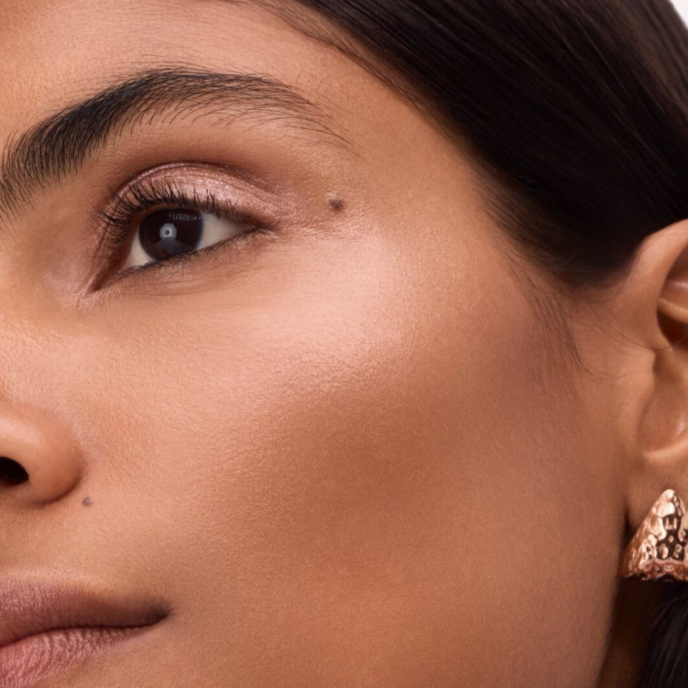 Gros plan d'un visage. Enlumineur appliqué. Boucles d'oreilles dorées.