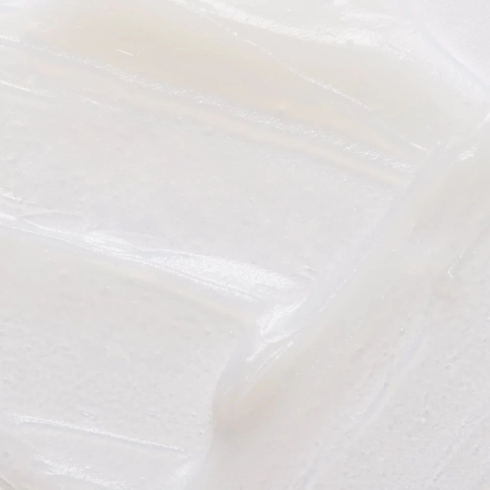 Produit blanc crémeux, gros plan. Surface lisse et brillante avec des stries visibles.