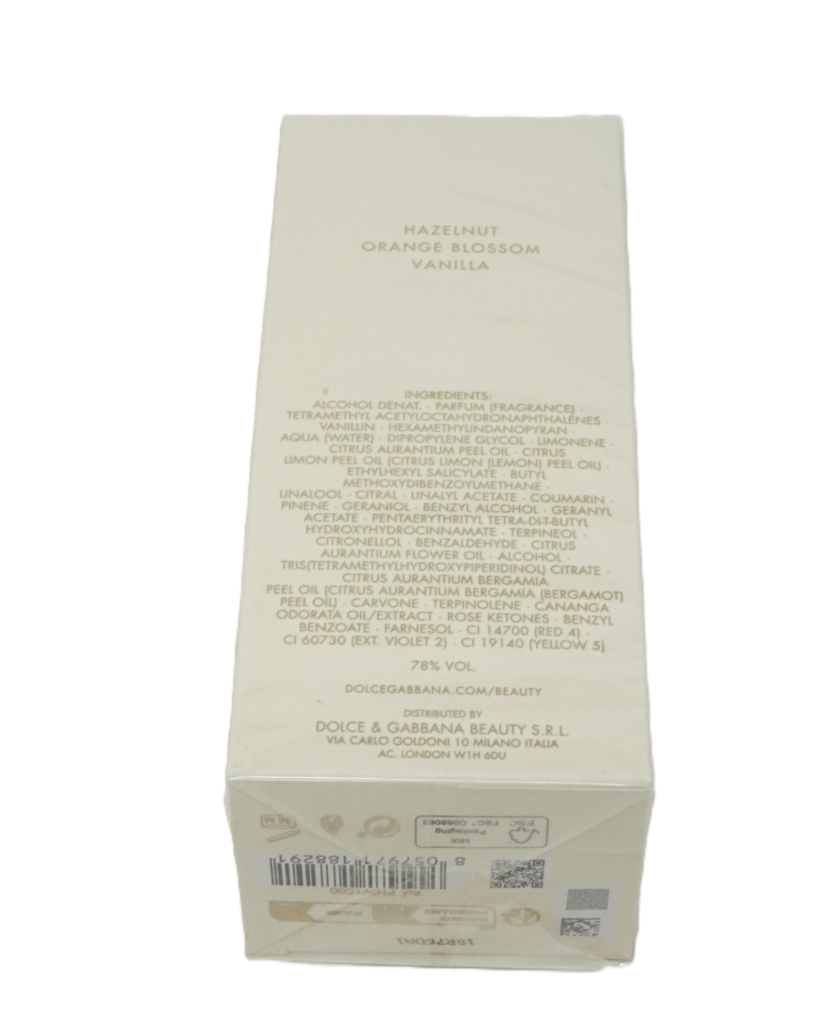 Boîte de parfum crème, texte visible. Ingrédients et marque Dolce & Gabbana. Inscription: Hazelnut, Orange Blossom, Vanilla.