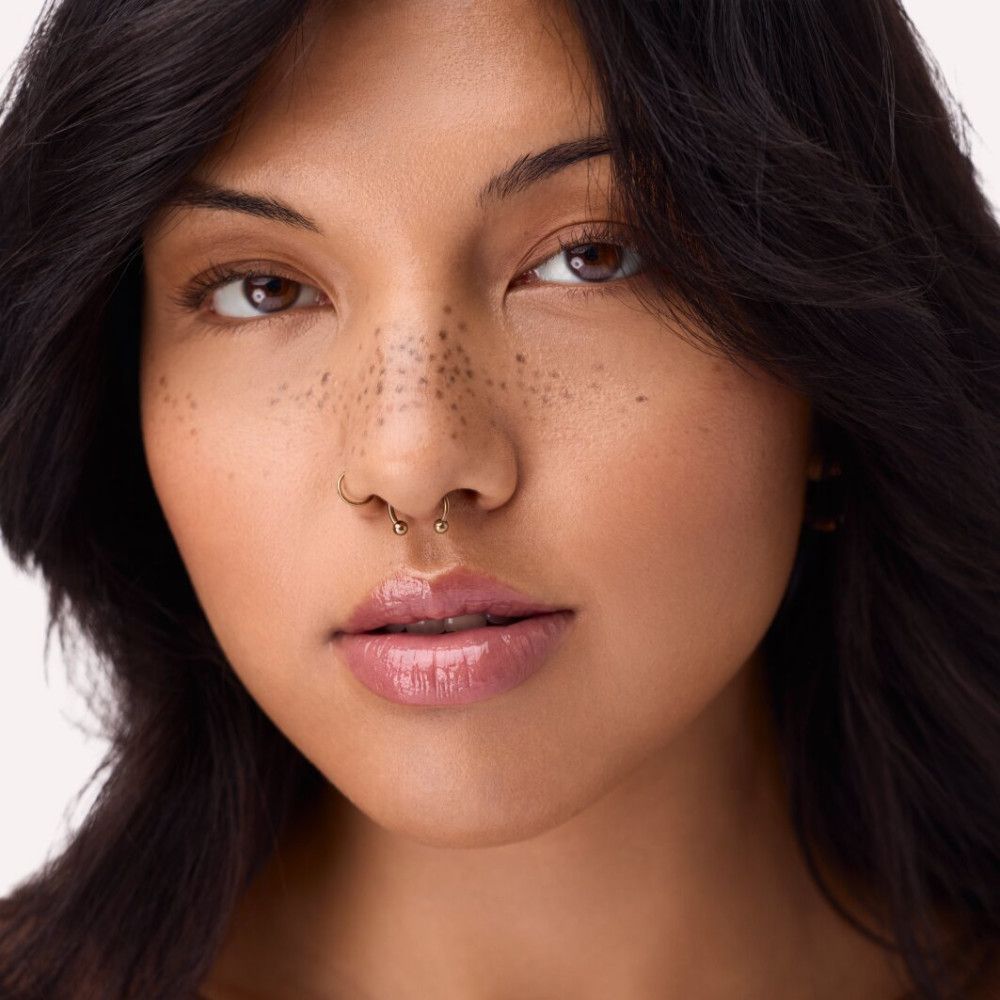 Portrait d'une femme avec du gloss appliqué. Les lèvres sont brillantes et roses.