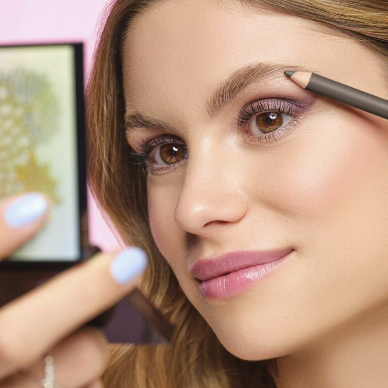 Vrouw met Artdeco Eye Brow Designer. Ze tekent haar wenkbrauw. Spiegel op de achtergrond.