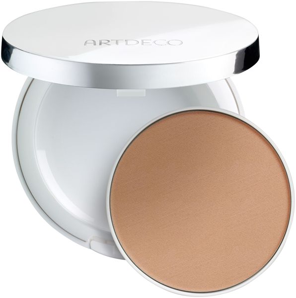Witte, ronde houder met open deksel. Bevat een ronde, beige foundation. Opschrift "ARTDECO" op deksel.