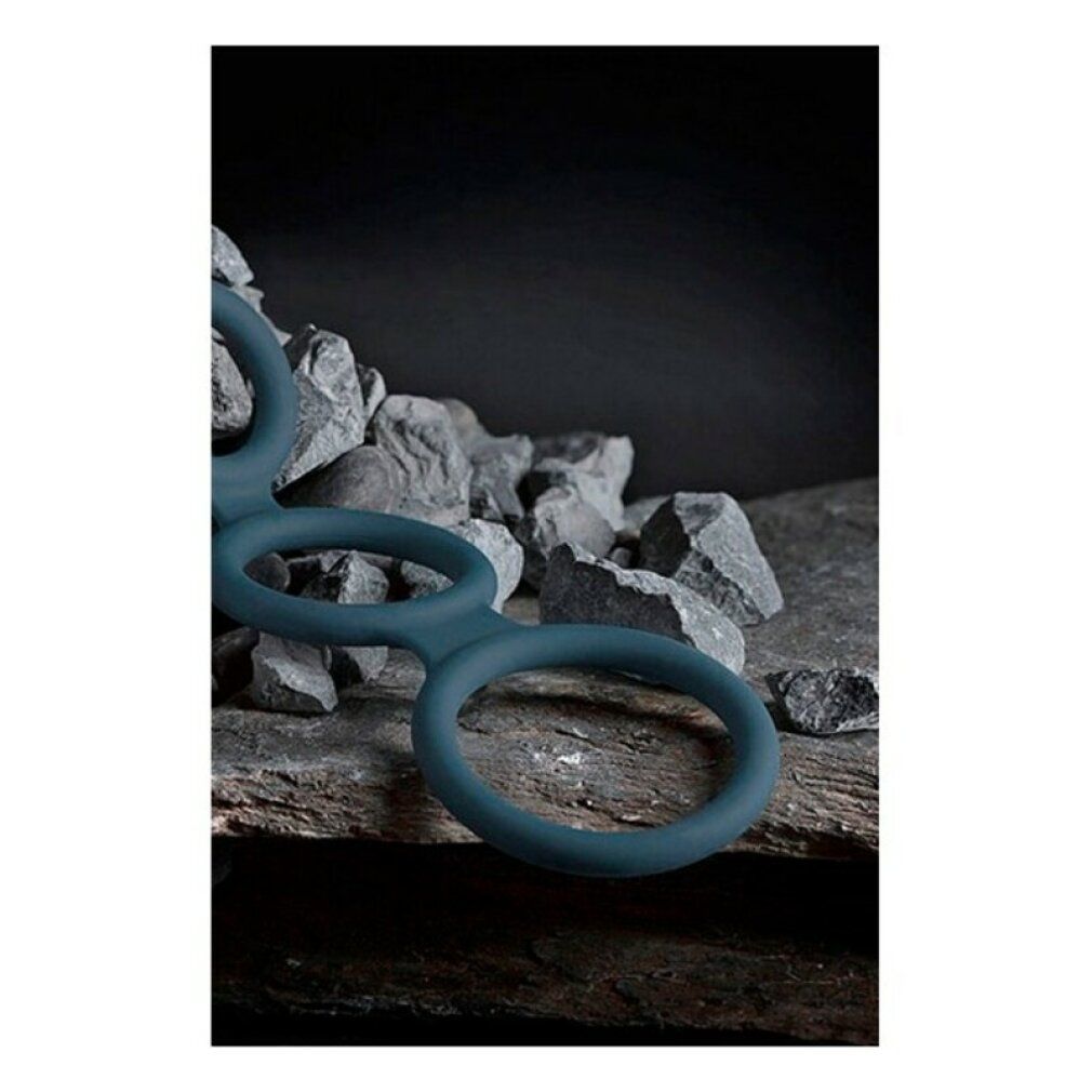 Anneau pénien bleu à trois anneaux. Placé sur un fond de pierres.