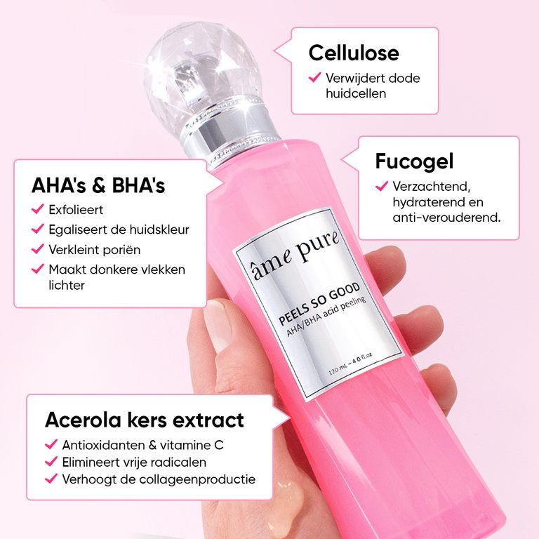 Close-up van een hand die een roze fles van de "Peels So Good" peeling van âme pure vasthoudt. Labels leggen ingrediënten uit.