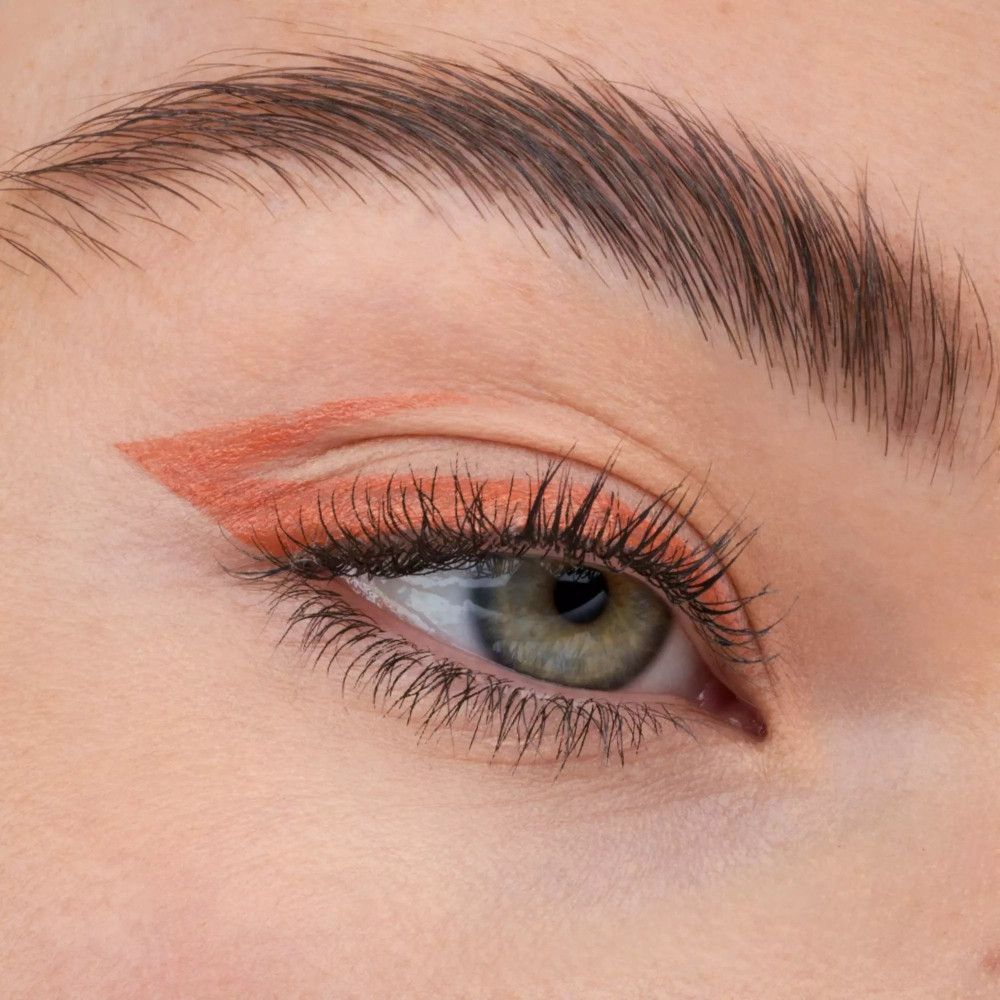 Œil avec trait d'eyeliner orange. Le trait de liner longe la ligne des cils supérieurs.