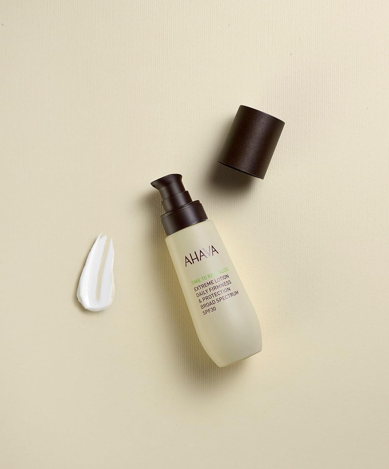 Ahava T.T.R. Extreme Lotion SPF30, open pompdosering, ernaast een witte lotionstaal.