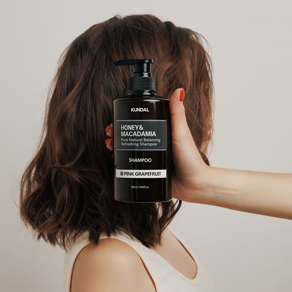 Een hand houdt een bruine shampoofles vast voor het haar van een persoon.