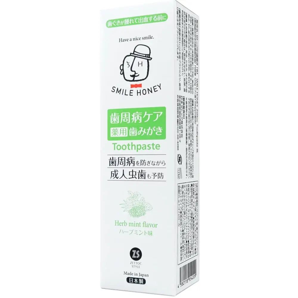 Witte tandpastaverpakking met groene en zwarte tekst. Opschrift: SMILE HONEY, Toothpaste, Herb mint flavor.