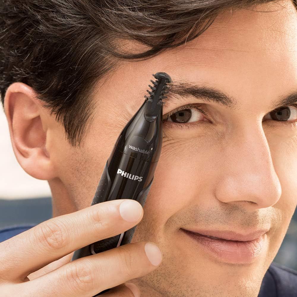 Man trimt wenkbrauwen met Philips trimmer. Zwart apparaat, blauw trimdeel.