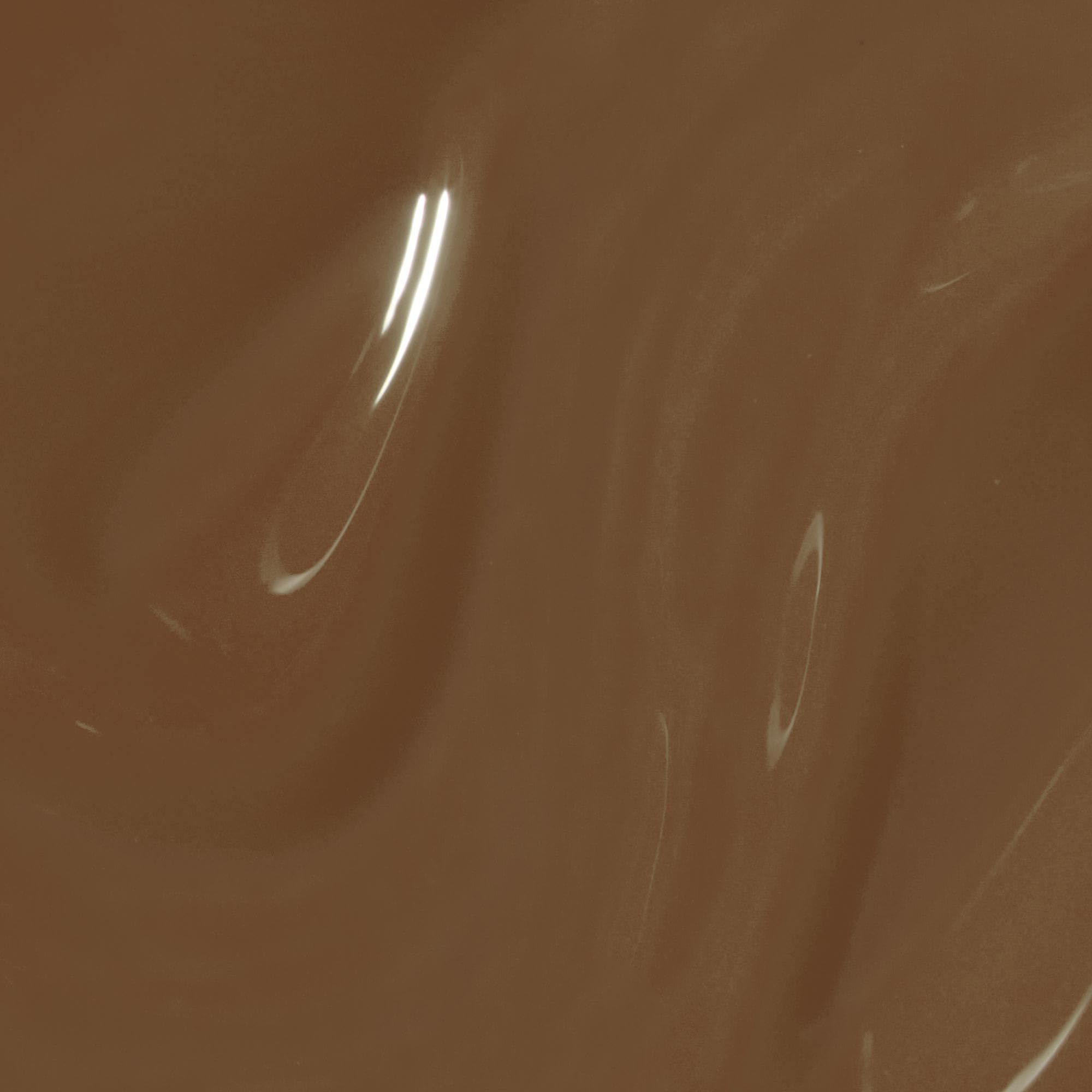 Liquide brun brillant avec des ondulations et des reflets lumineux.