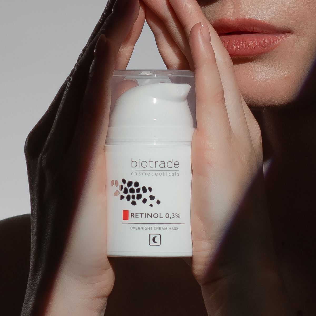 Flacon blanc Biotrade, Retinol 0,3% et masque de nuit. Mains tenant le flacon.