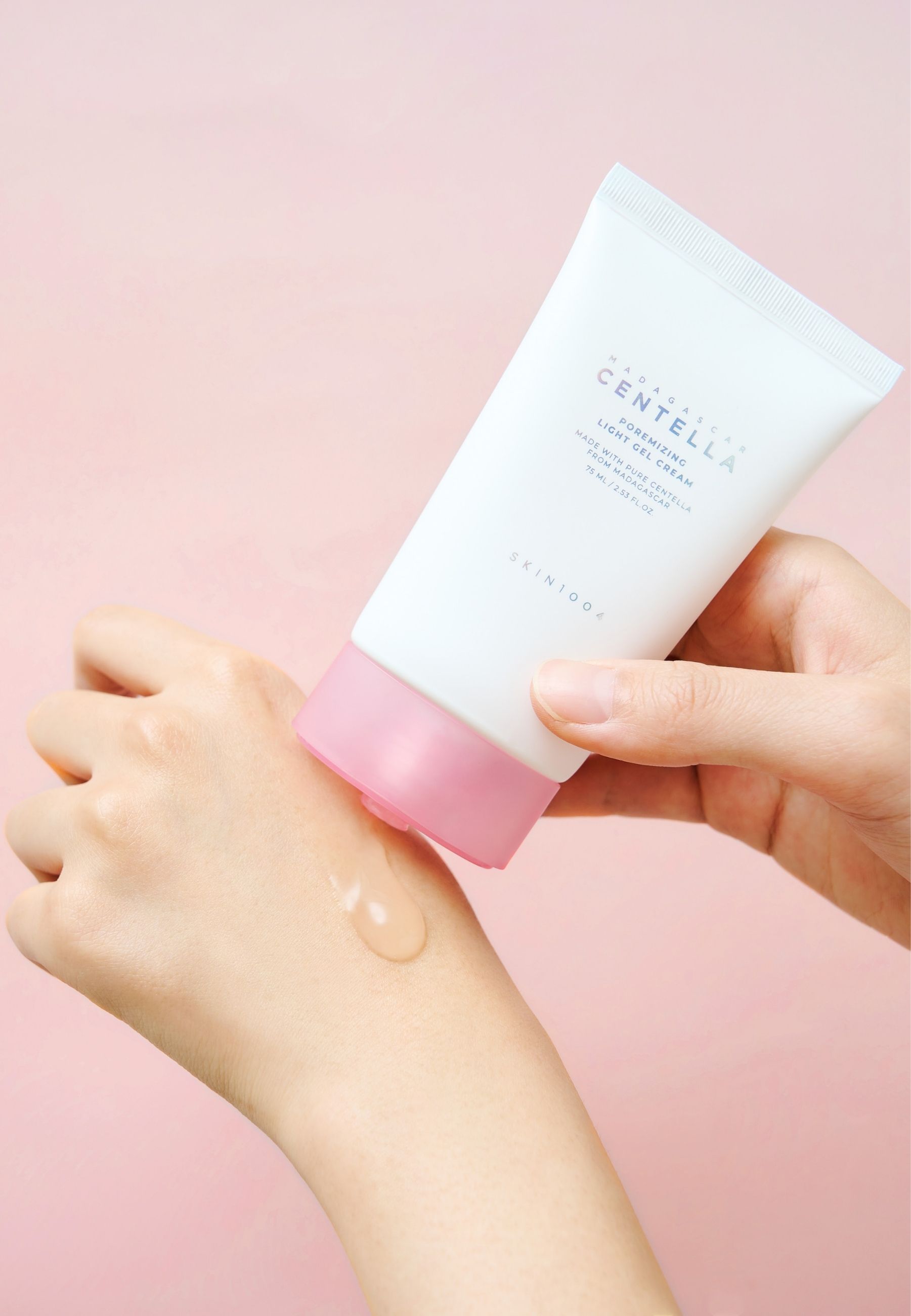 Mains tenant un tube. Gel appliqué sur la main. Inscription : MADAGASCAR CENTELLA Poremizing Light Gel Cream. Marque SKIN1004.