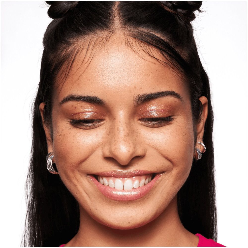 Gros plan d'un visage souriant. La peau est lisse et uniforme. Yeux fermés.