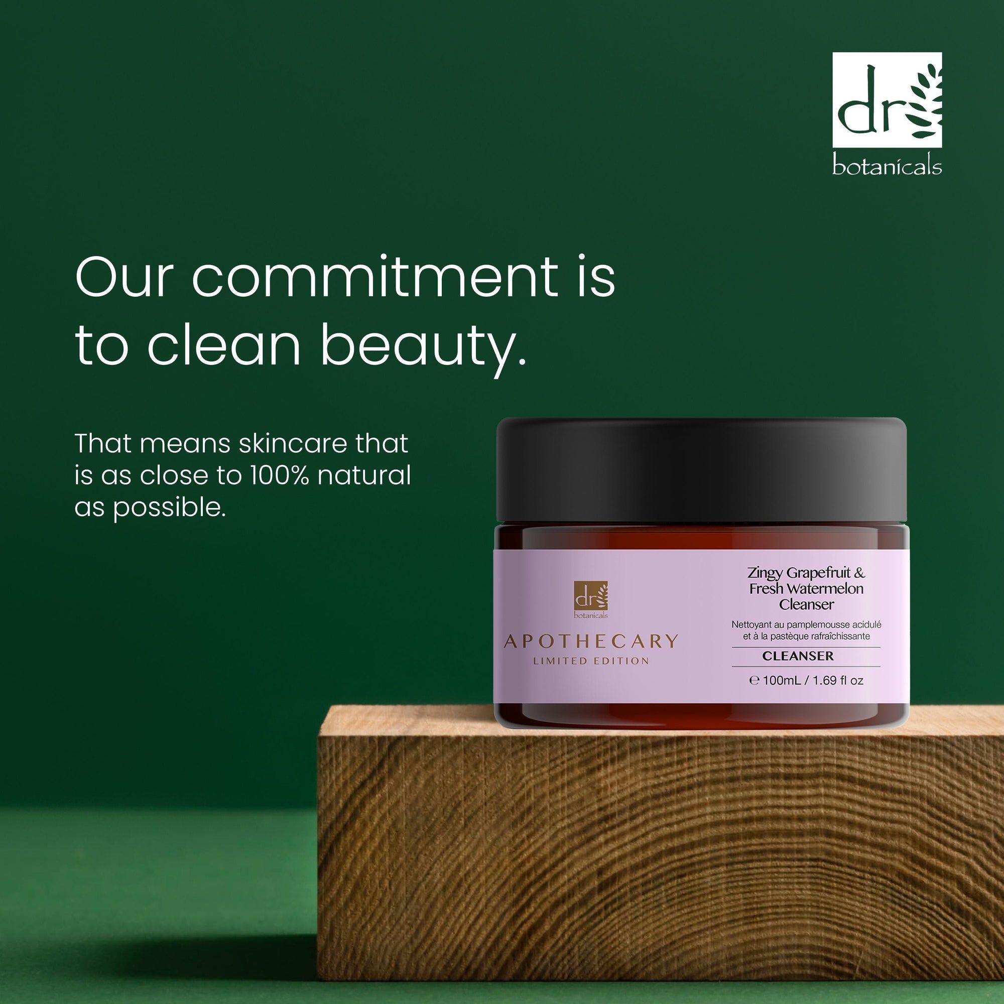 Bruine pot met zwarte deksel. Label met productnaam en merk. Tekst: Our commitment is to clean beauty. Op houten blok.