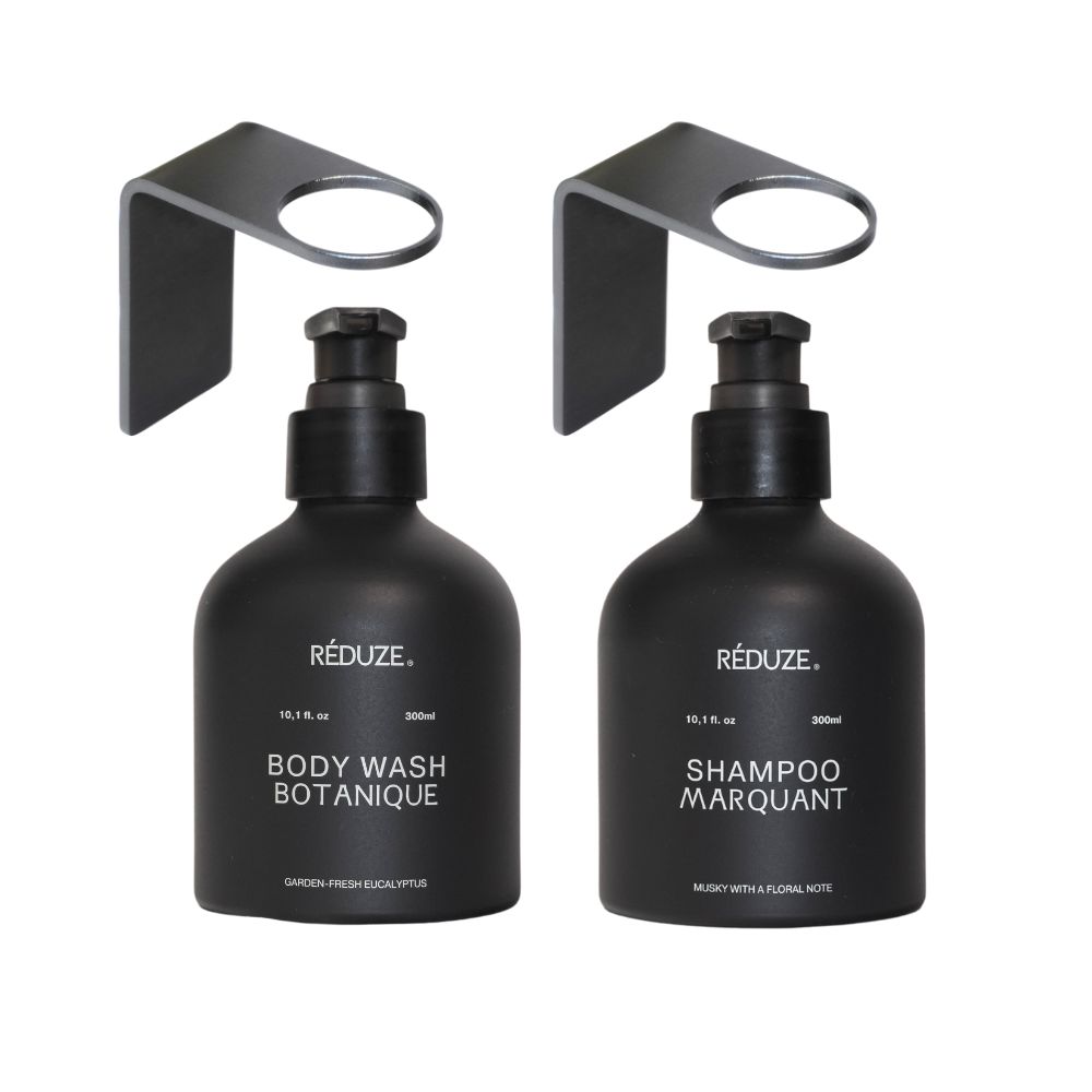 Deux flacons noirs avec supports muraux. Inscription : RÉDUZE, Body Wash Botanique, Shampoo Marquant.