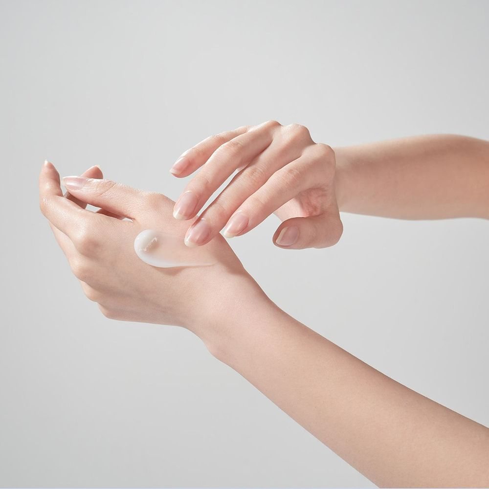 Mains avec crème. Crème sur la paume. Pas d'emballage visible.