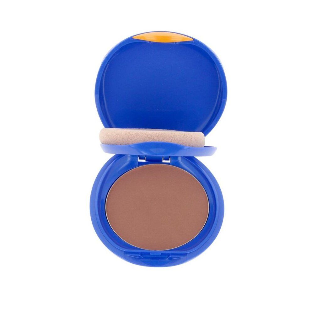 Boîtier compact bleu ouvert. Contient une éponge et une poudre brune.
