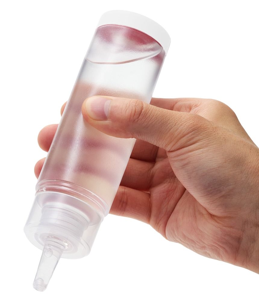 Hand houdt een Tenga Lotion Mild fles vast met heldere inhoud.