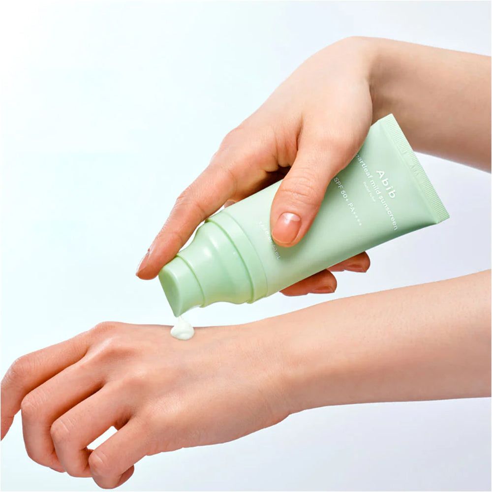 Une main dépose la crème solaire Abib Heartleaf Mild SPF 50+ PA++++ sur une autre main.