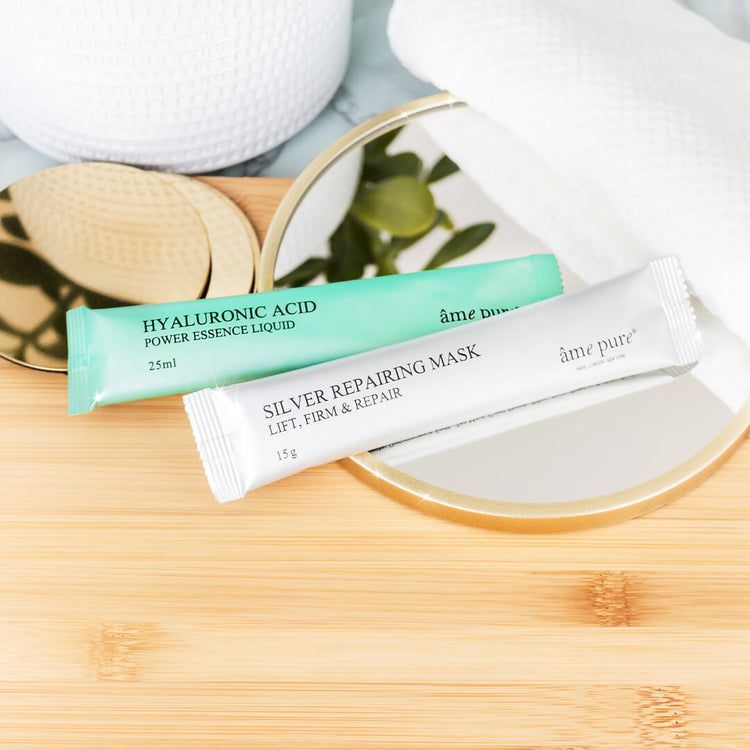 Deux sachets de masques sur bois. Vert et argent. Texte : âme pure, Hyaluronic Acid, Silver Repairing Mask. Miroir en arrière-plan.