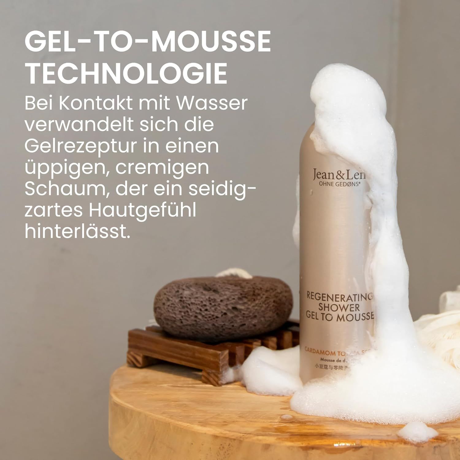 Beige fles met witte dop. Schuim stroomt eruit. Tekst: Jean & Len, Regenerating Shower Gel To Mousse.