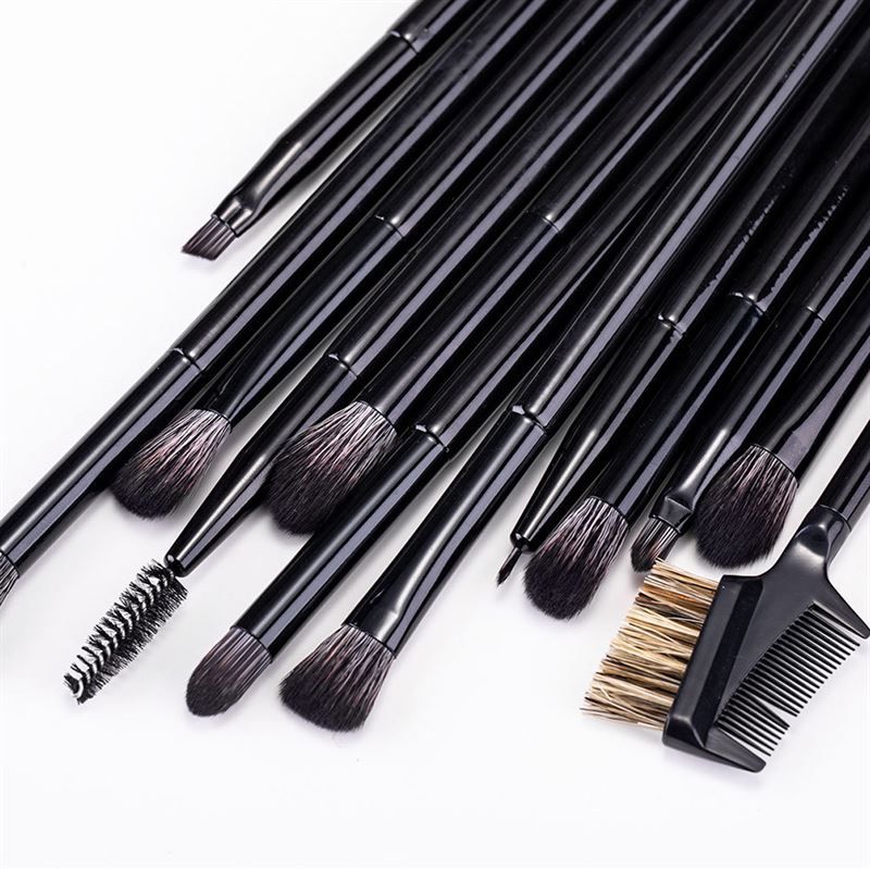 Ensemble de pinceaux noirs pour fard à paupières et sourcils avec un peigne, disposés sur fond clair.