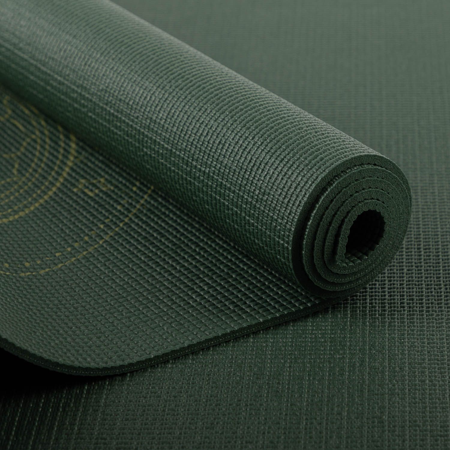 Opgerolde groene yogamat. Gouden geometrische patronen zichtbaar. Gestructureerd oppervlak. Close-up.