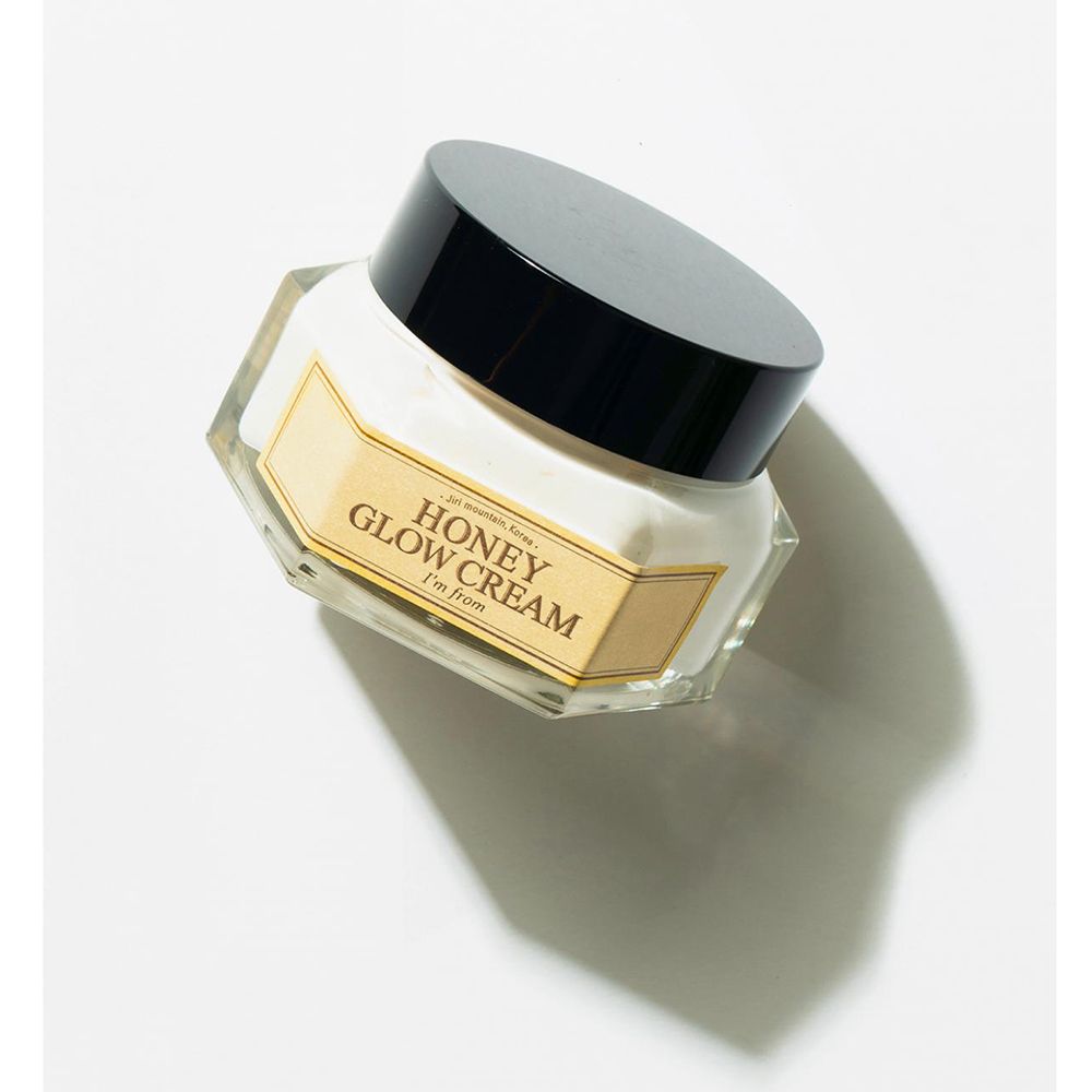 Pot de crème avec couvercle noir. Inscription: HONEY GLOW CREAM, I'm from. Étiquette jaune.