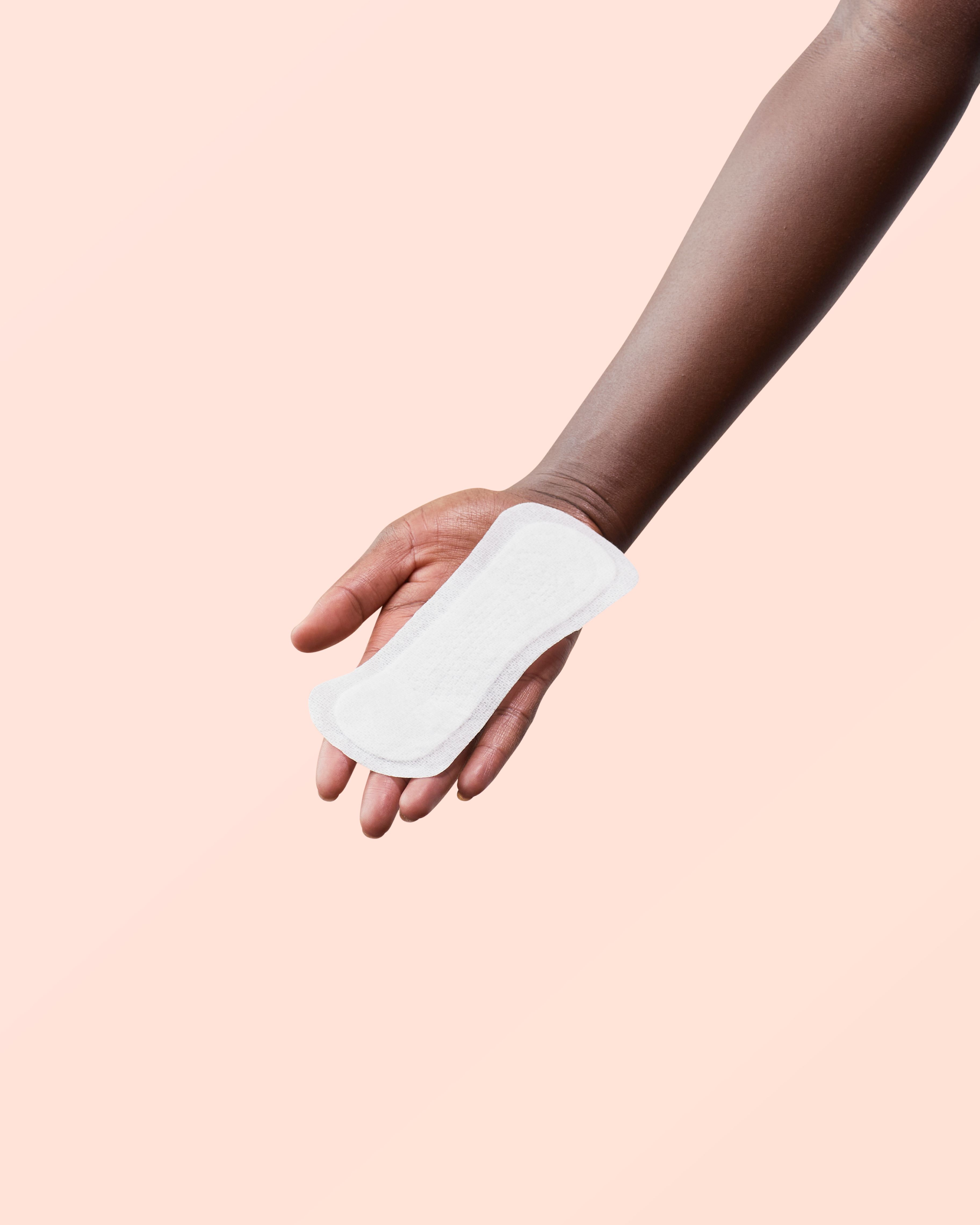 Main tenant une protège-slip blanc. Sur fond rose.