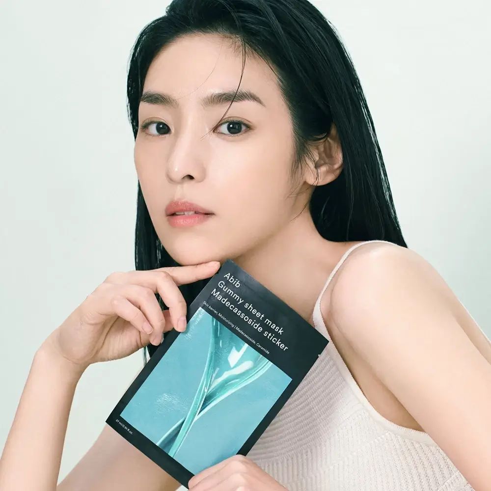 Une femme tient l'Abib Gummy Sheet Mask Madecassoside Sticker devant elle.