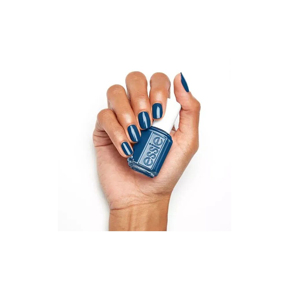 Hand met Essie nagellak in donkerblauw. Gelakte nagels. Witte dop, vierkante fles, Essie logo.