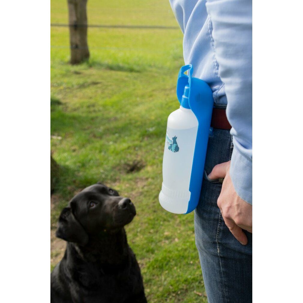 Personne portant une bouteille d'eau bleue à la ceinture. Chien noir qui regarde. La bouteille a un support bleu et un récipient blanc.