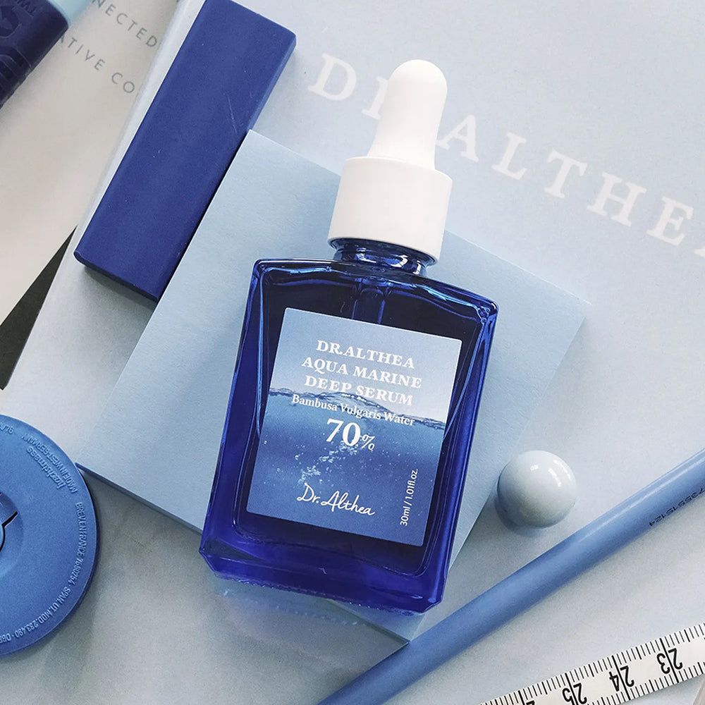Dr. Althea Aqua Marine Deep Serum fles op blauwe achtergrond met accessoires.