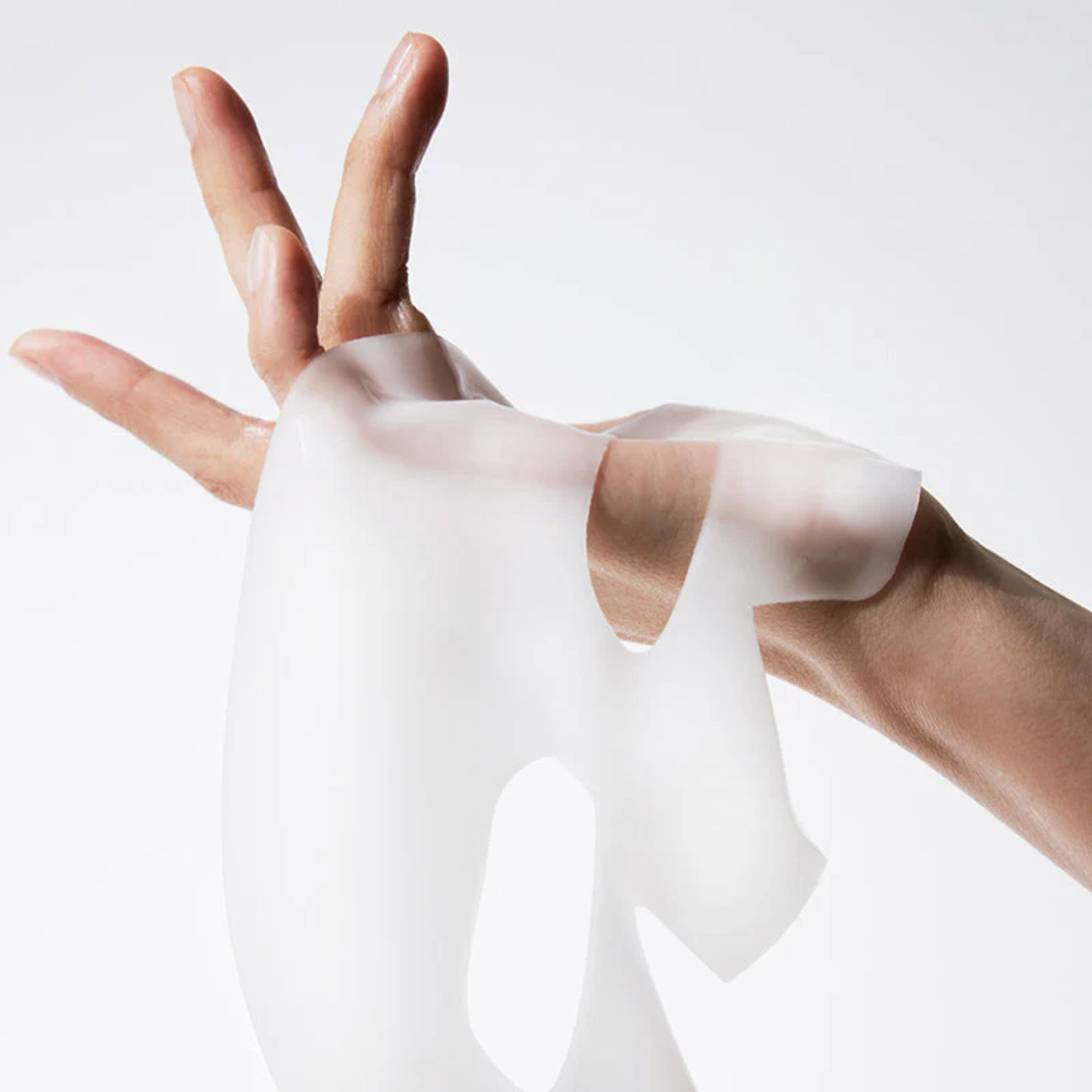 Mains tenant un masque facial transparent. Le masque a des ouvertures pour les yeux, le nez et la bouche. Fabriqué dans un matériau souple.
